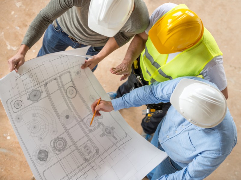 Professional engineering consultants discussing project blueprints and providing expert construction guidance.